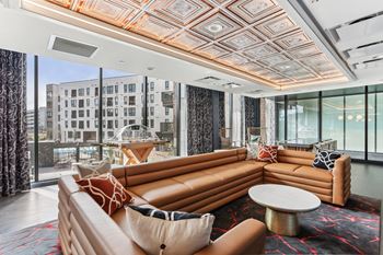 A living room with a large orange couch and a patterned rug.